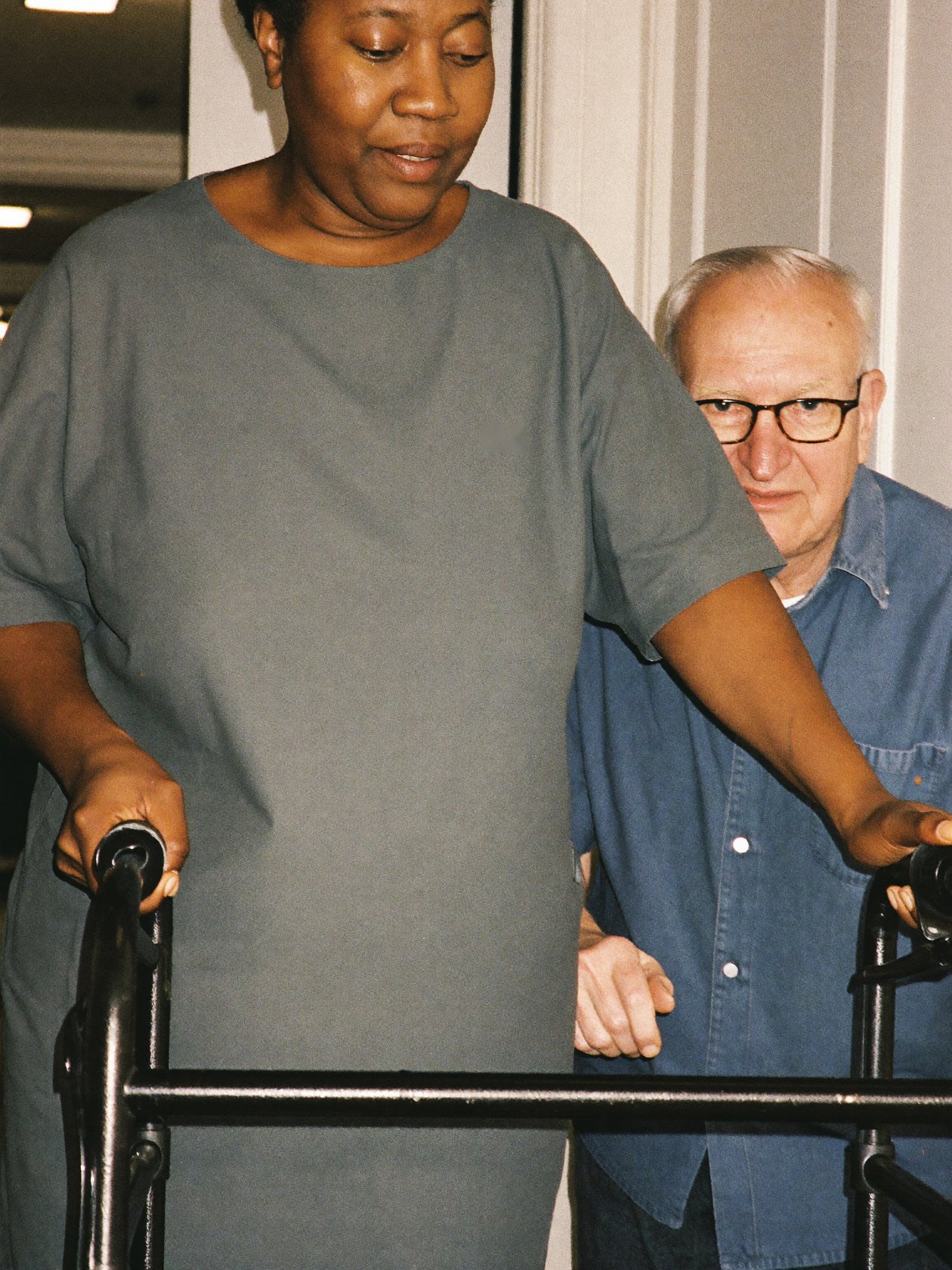 A caregiver helping a senior man walk safely at home