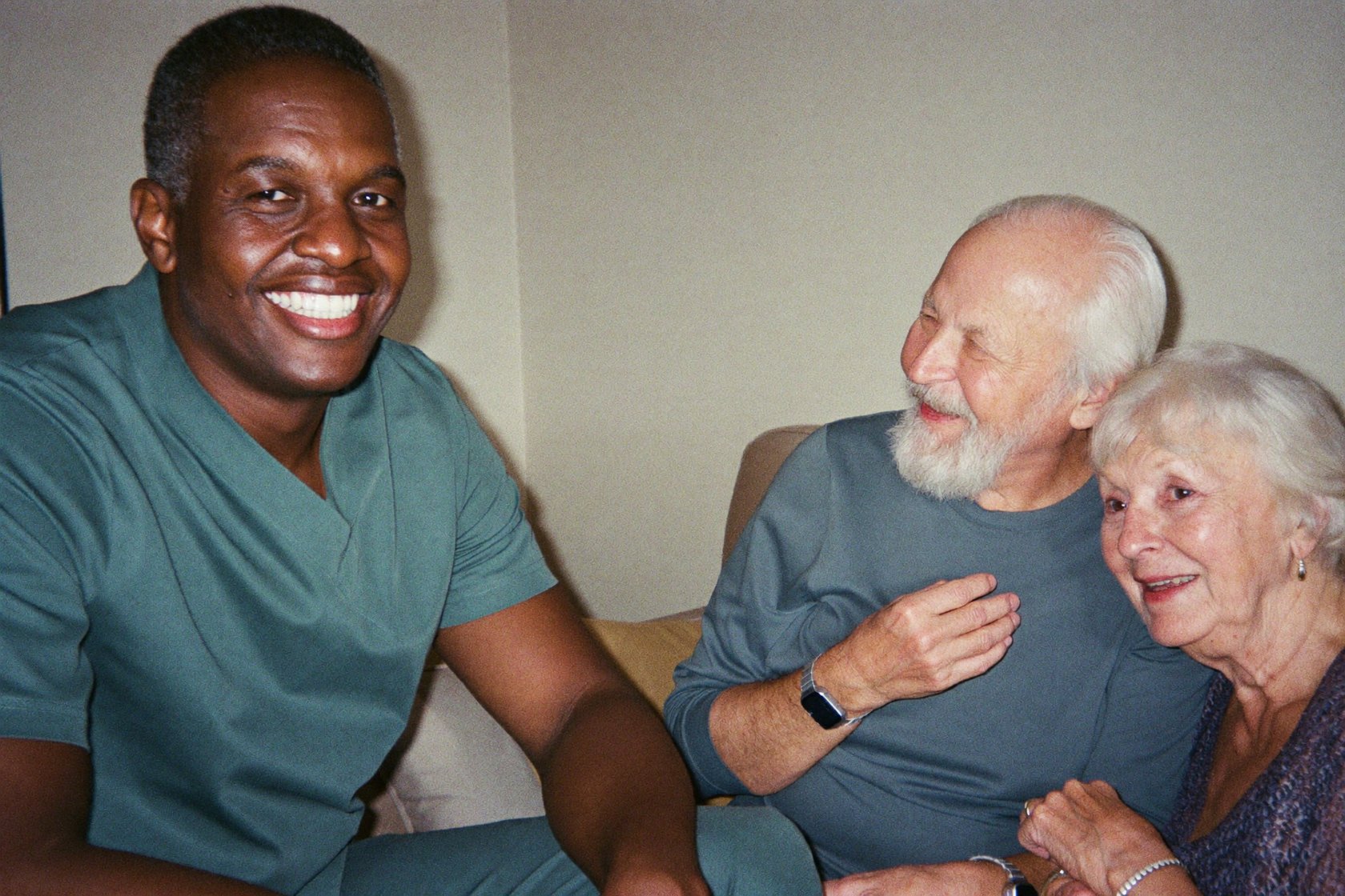 A caregiver chatting with a senior couple on their living room sofa